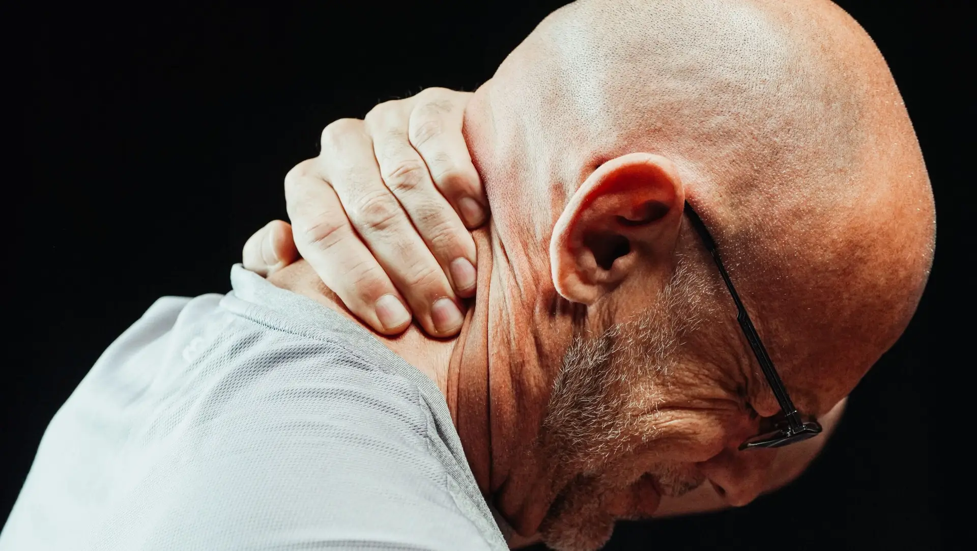 Side view of senior man holding neck with visible discomfort, highlighting neck pain relief.