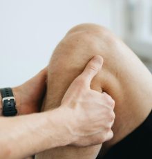 Close-up of a physiotherapist massaging a patient's knee during therapy.